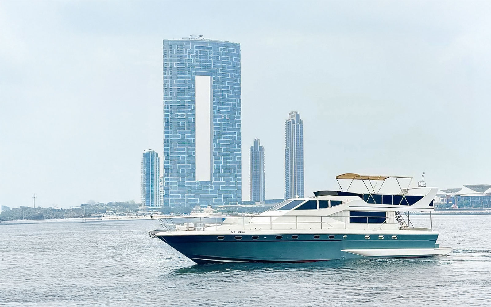 Luxury yacht cruising near Dubai Harbour with city skyline in background.