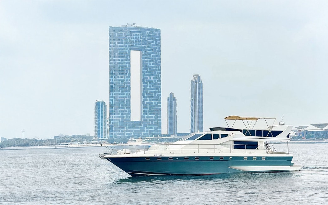 Luxury yacht cruising near Dubai Harbour with city skyline in background.
