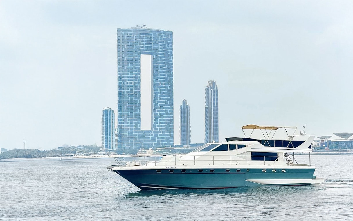 Luxury yacht cruising near Dubai Harbour with city skyline in background.