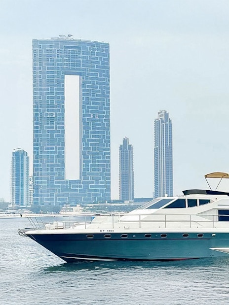 Luxury yacht cruising near Dubai Harbour with city skyline in background.