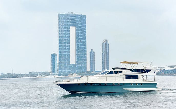 Luxury yacht cruising near Dubai Harbour with city skyline in background.