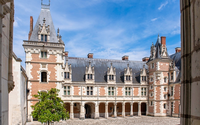 Royal Blois Castle courtyard with ornate architecture and blue sky.