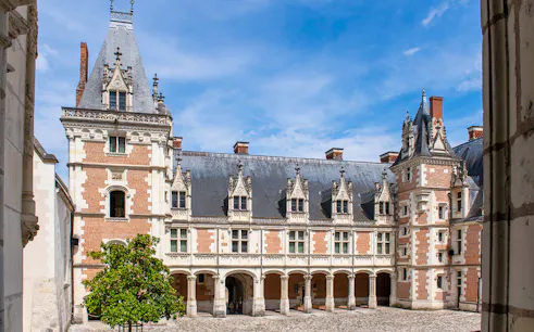 Royal Blois Castle courtyard with ornate architecture and blue sky.