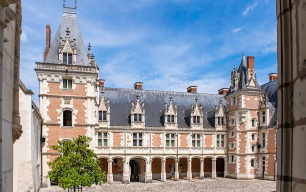 Royal Blois Castle courtyard with ornate architecture and blue sky.