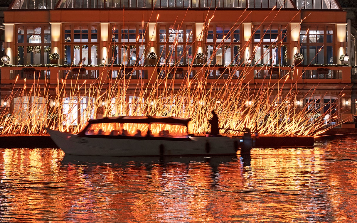 Canal boat passing illuminated art installation during Amsterdam Light Festival.
