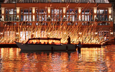 Canal boat passing illuminated art installation during Amsterdam Light Festival.