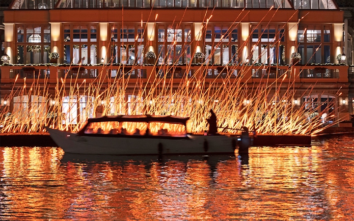 Canal boat passing illuminated art installation during Amsterdam Light Festival.