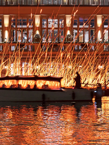 Canal boat passing illuminated art installation during Amsterdam Light Festival.