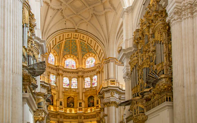 Interior of the Royal Chapel, Granada Cathedral, featuring ornate architecture and stained glass windows.
