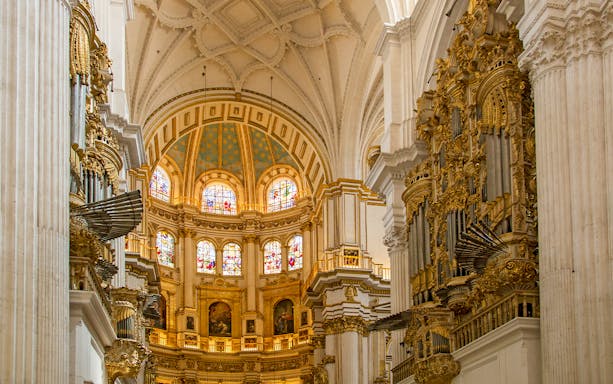 Interior of the Royal Chapel, Granada Cathedral, featuring ornate architecture and stained glass windows.