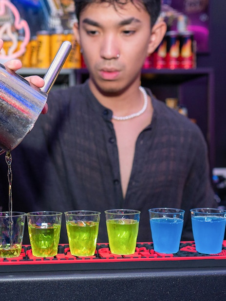 Bartender pouring colorful shots at a bar in Rome.