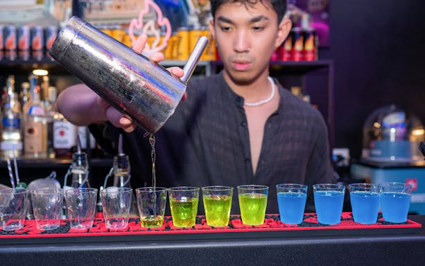 Bartender pouring colorful shots at a bar in Rome.