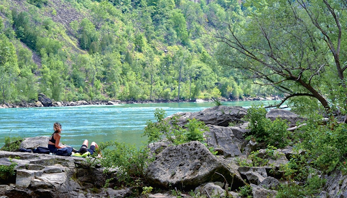 Hikers resting on rocks along Niagara River gorge on Niagara Glen trails, Canada.