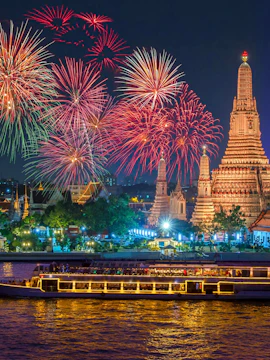 Wat Arun illuminated with fireworks and a cruise ship on the Chao Phraya River, Bangkok, Thailand.