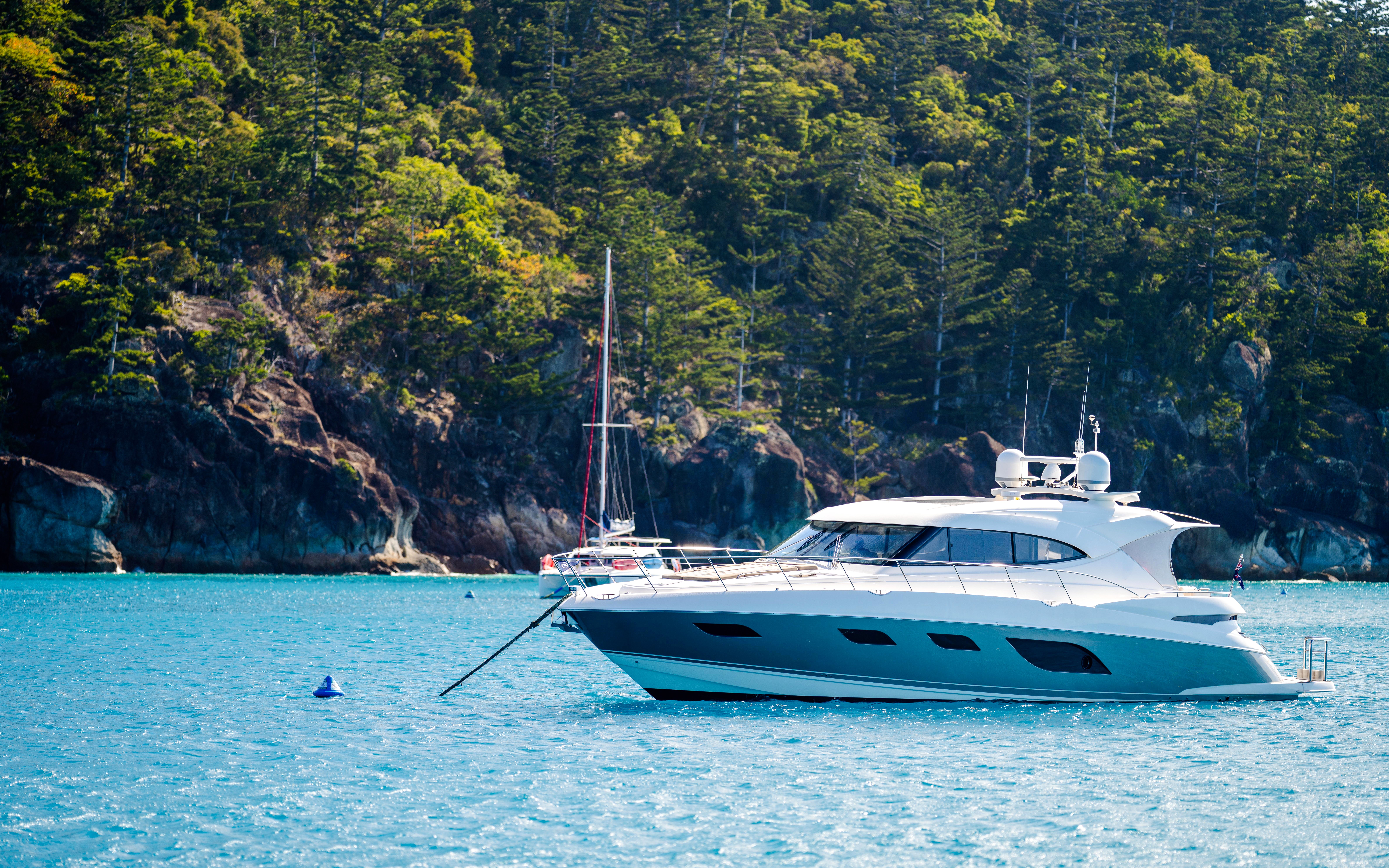 Tourist boats in the Whitsundays, Queensland, Australia, near lush coastline.