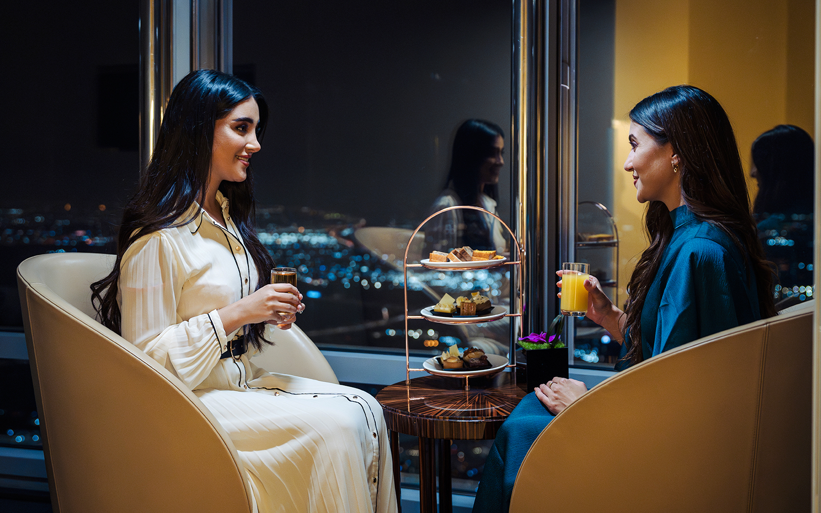 Guests enjoying drinks and desserts at Burj Khalifa Level 152 lounge with city view.