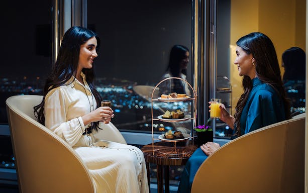 Guests enjoying drinks and desserts at Burj Khalifa Level 152 lounge with city view.