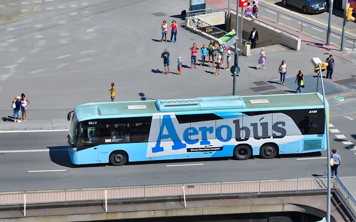 Aerobus in Barcelona city center with tourists nearby.