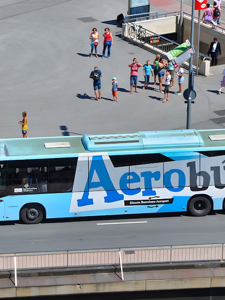 Aerobus in Barcelona city center with tourists nearby.