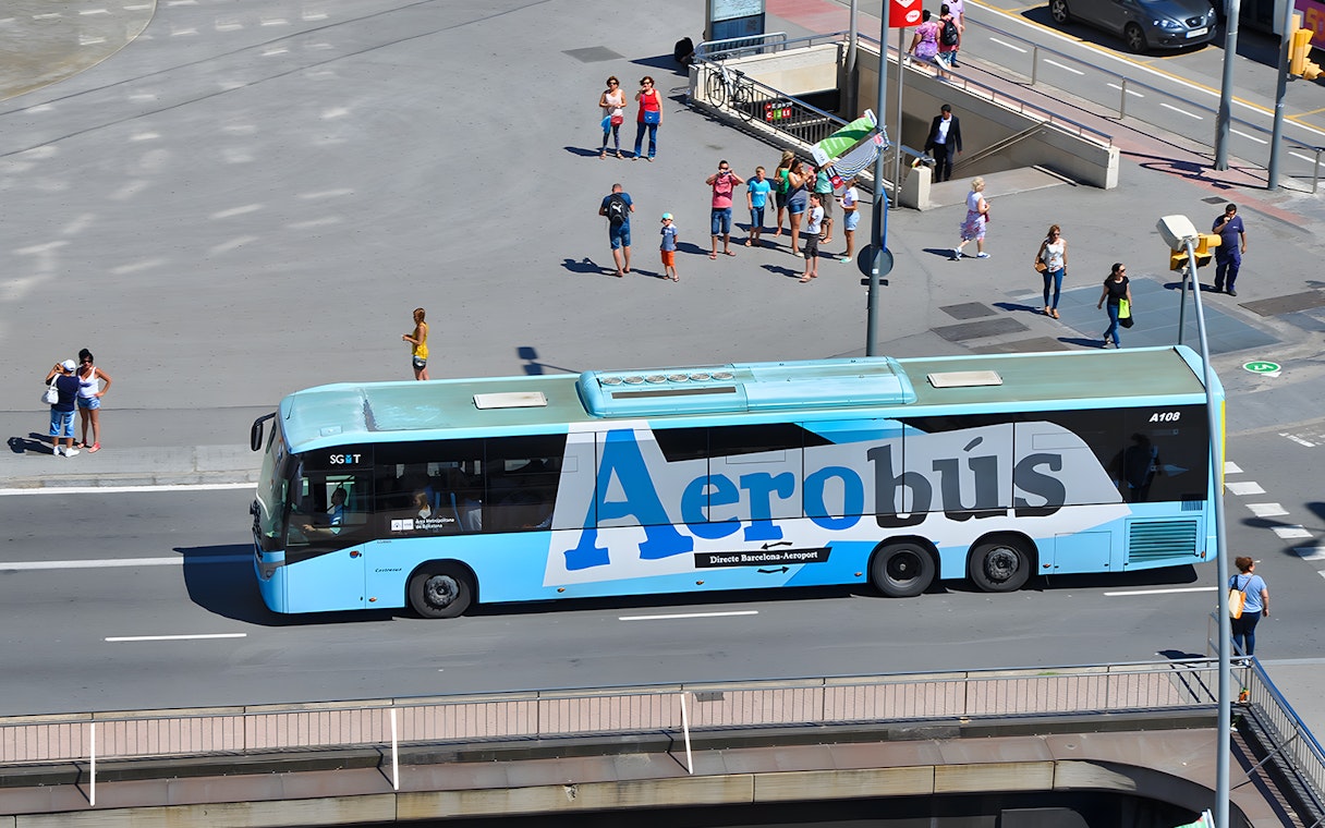 Aerobus in Barcelona city center with tourists nearby.