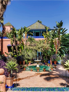 Jardin Majorelle courtyard with fountain, lush greenery, and vibrant blue building in Marrakech, Morocco.