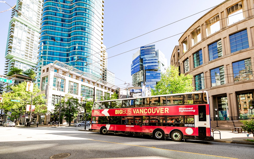 Big Bus Vancouver tour passing modern skyscrapers and historic buildings in downtown Vancouver.