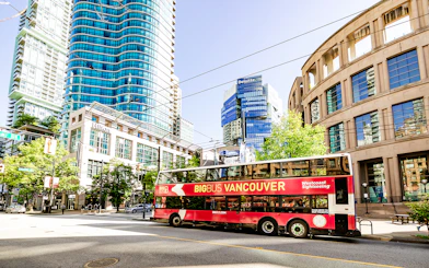Big Bus Vancouver tour passing modern skyscrapers and historic buildings in downtown Vancouver.