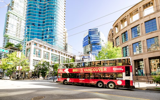 Big Bus Vancouver tour passing modern skyscrapers and historic buildings in downtown Vancouver.