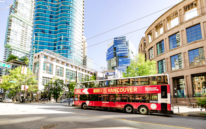 Big Bus Vancouver tour passing modern skyscrapers and historic buildings in downtown Vancouver.