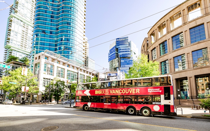 Big Bus Vancouver tour passing modern skyscrapers and historic buildings in downtown Vancouver.