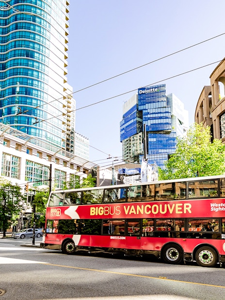 Big Bus Vancouver tour passing modern skyscrapers and historic buildings in downtown Vancouver.