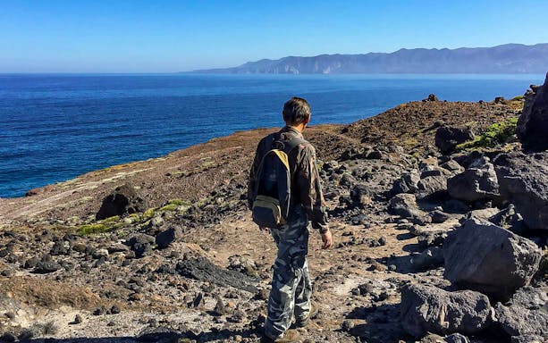 Hiker on Tonnare trail overlooking the sea in Gonnesa, Sardinia.