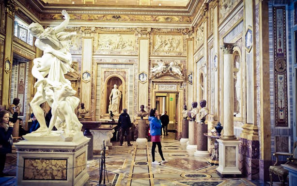 Borghese Gallery interior with sculptures and visitors exploring the ornate hall.
