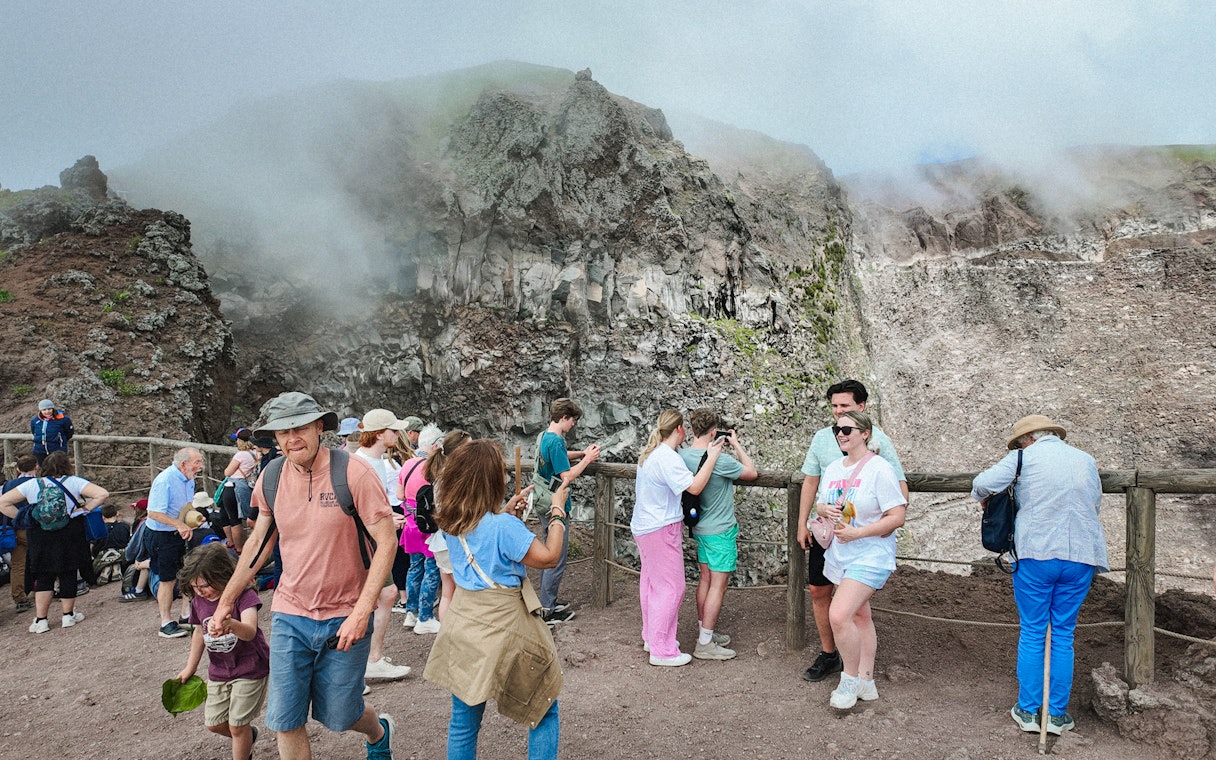Visitors taking photos at the Mount Vesuvius crater viewpoint.
