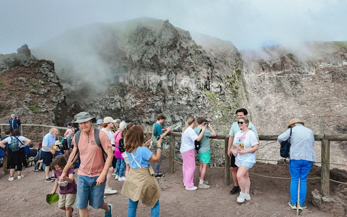 Visitors taking photos at the Mount Vesuvius crater viewpoint.