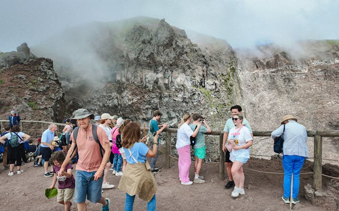 Visitors taking photos at the Mount Vesuvius crater viewpoint.