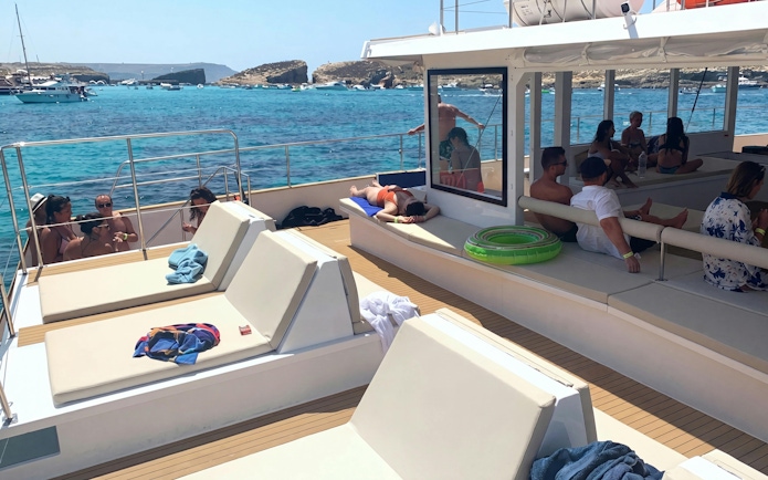 Tourists relaxing on a boat during Blue Lagoon sunset cruise, Malta.