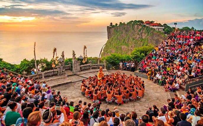 Uluwatu Kecak and Fire Dance performance at sunset with ocean view in Bali.