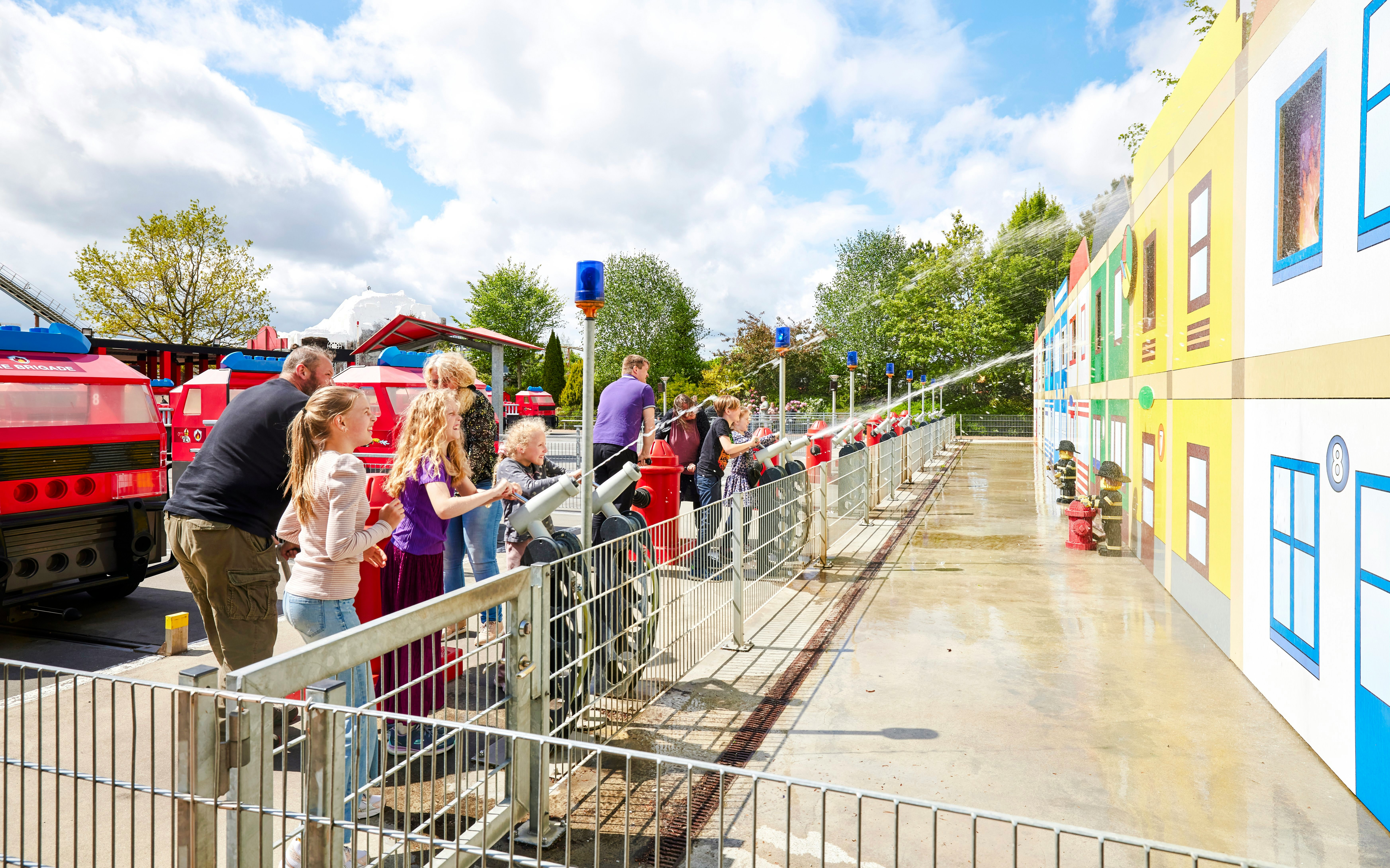Children playing with water cannons at LEGOLAND Billund fire station attraction.