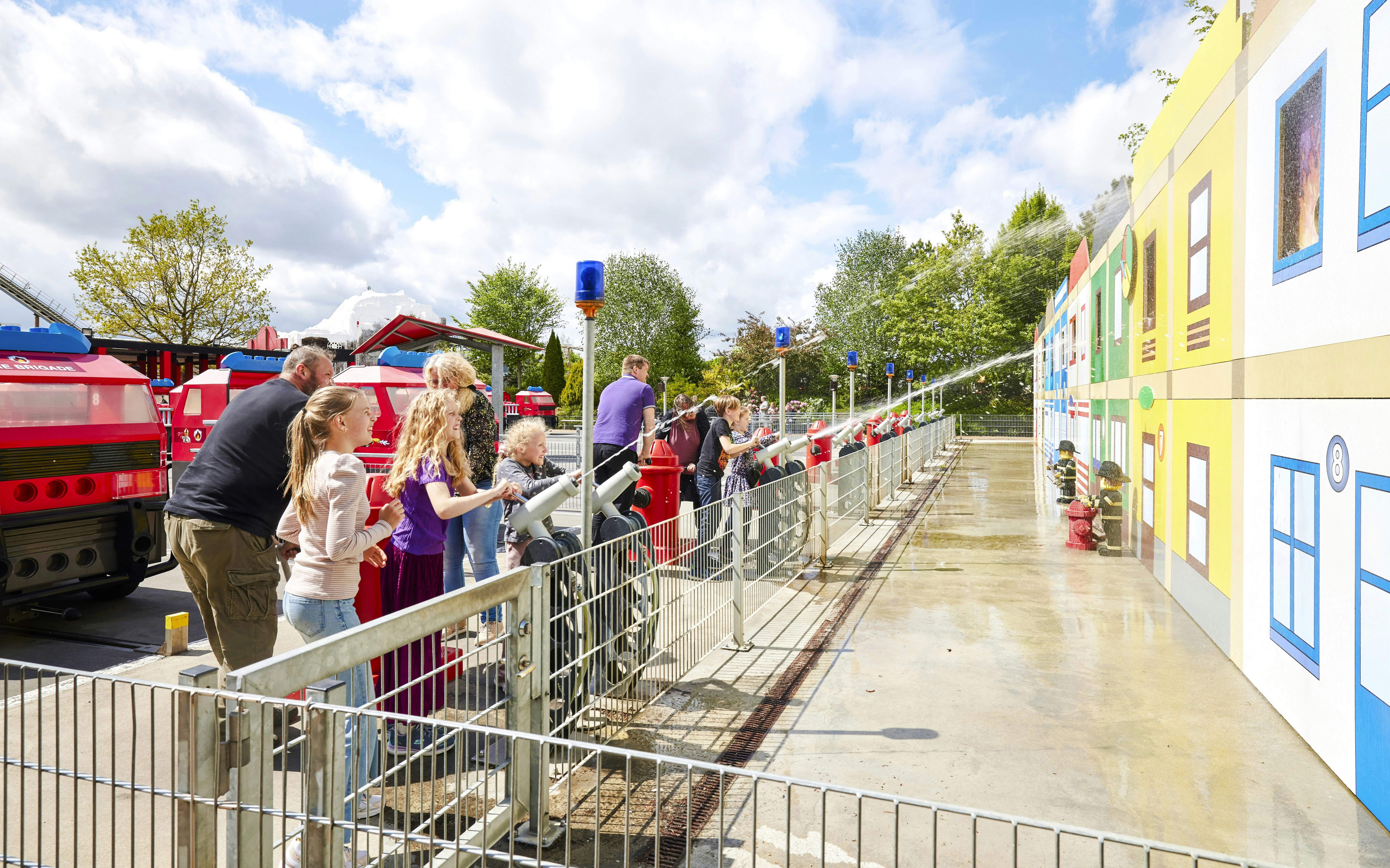 Children playing with water cannons at LEGOLAND Billund fire station attraction.