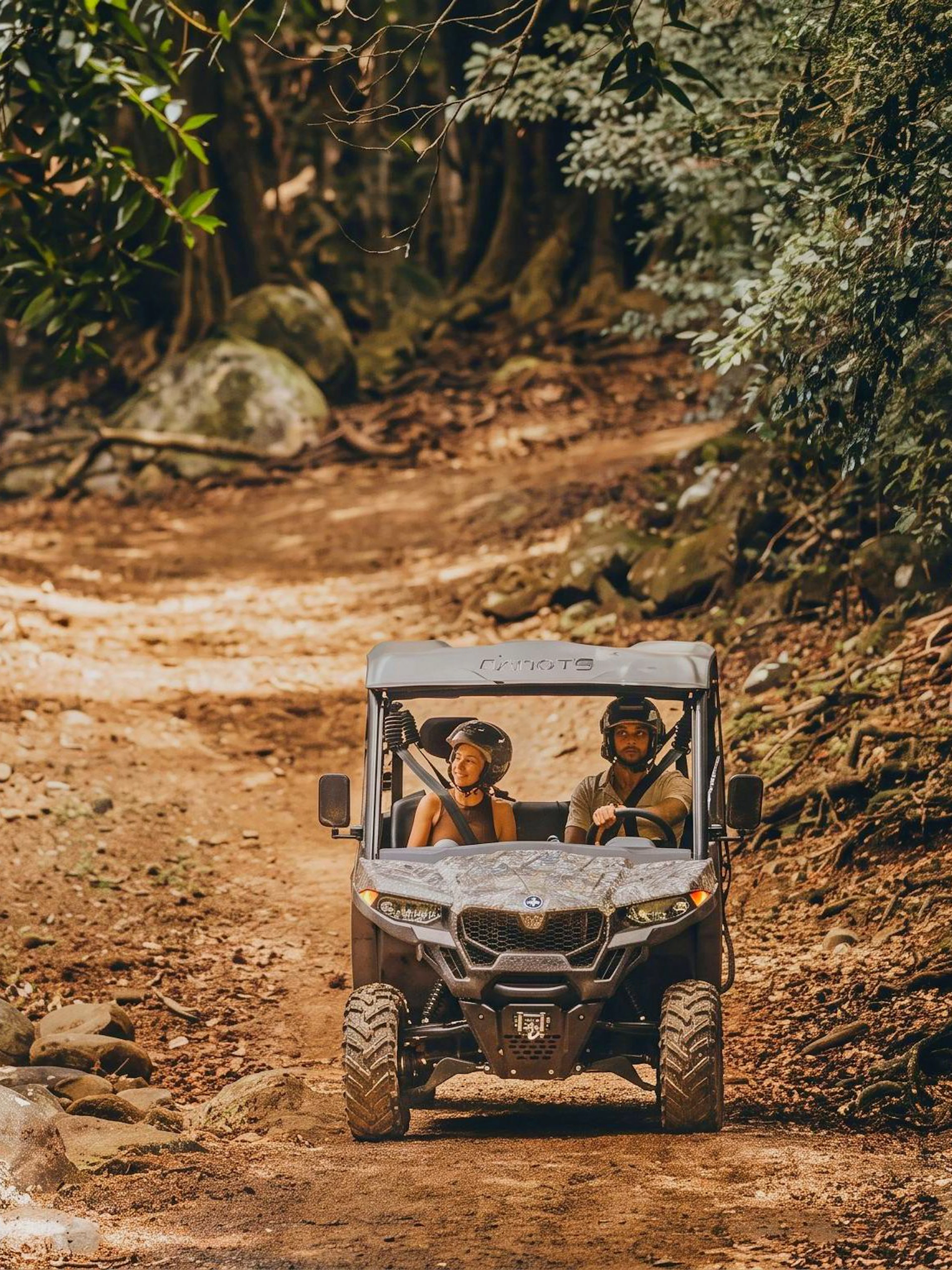 Two people driving a buggy through a forest trail in Bel Ombre.