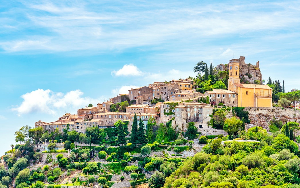 Medieval village of Eze on a hillside, featuring stone buildings and lush greenery, French Riviera.