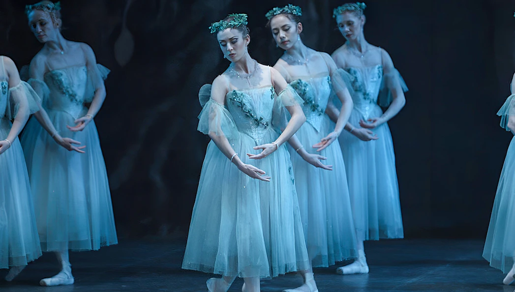 Ballet dancers performing "Giselle" in ethereal costumes on stage.