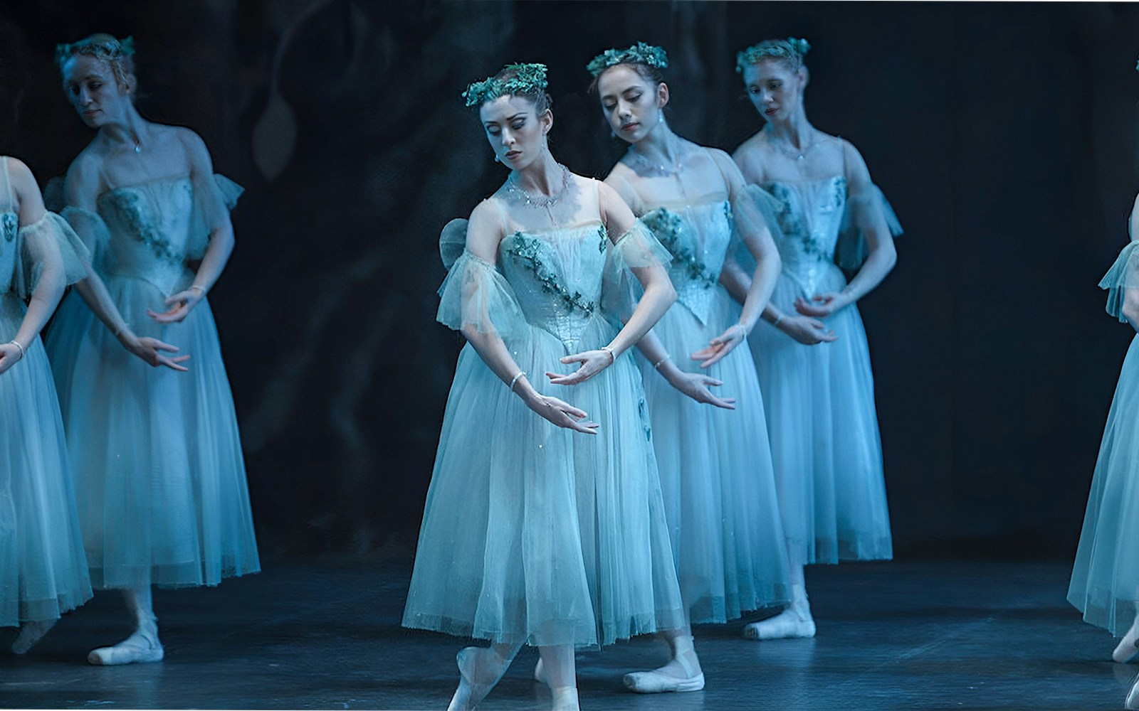 Ballet dancers performing "Giselle" in ethereal costumes on stage.