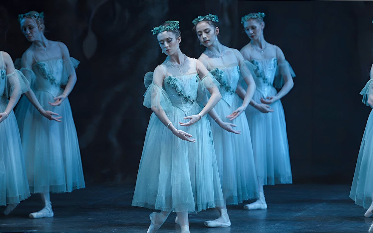 Ballet dancers performing "Giselle" in ethereal costumes on stage.
