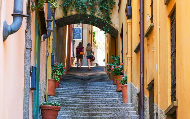 Narrow stone alley with potted flowers in Bellagio, Lake Como tour.