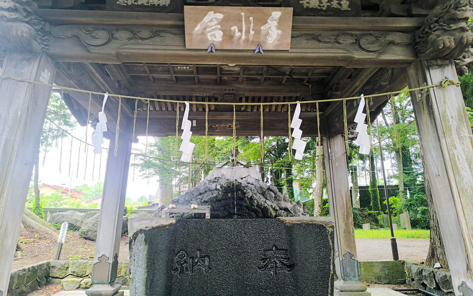 Shrine structure at Oshino Hakkai, Japan, with traditional wooden architecture and sacred ropes.