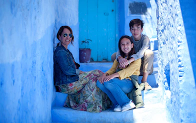 Tourist family sitting on blue steps in Chefchaouen, Morocco.