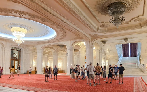 Guided tour group in the grand hall of the Palace of Parliament, near the staircase.
