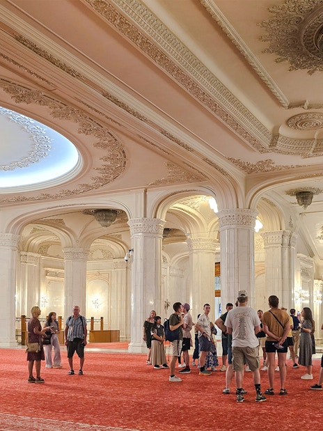 Guided tour group in the grand hall of the Palace of Parliament, near the staircase.